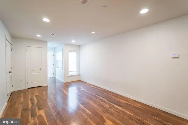 a view of an empty room with wooden floor and closet