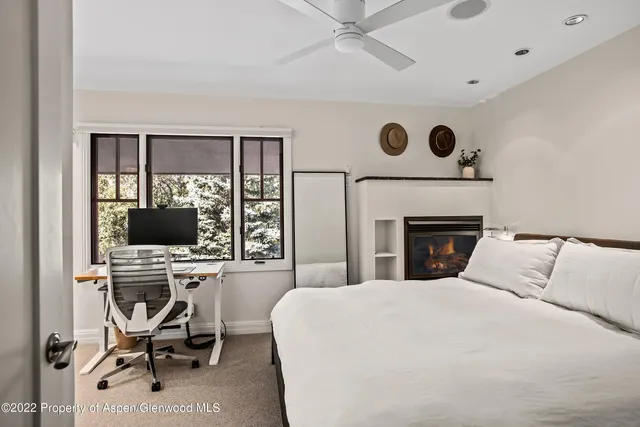 a bedroom with a bed and a computer on a desk next to a window