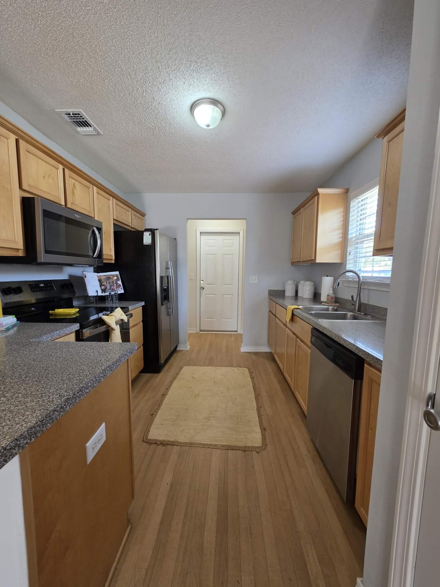 8347 Tavira Street Navarre, FL 32566 - Photo 14 of 49 a kitchen with stainless steel appliances granite countertop a refrigerator a stove top oven a sink dishwasher and wooden cabinets with wooden floor