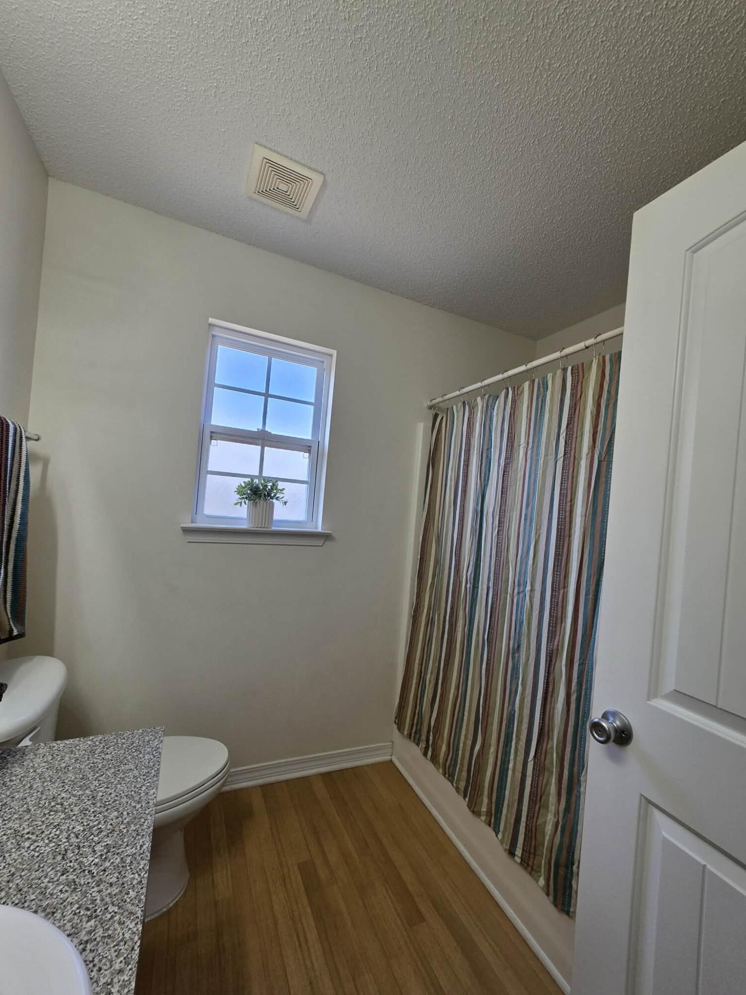 8347 Tavira Street Navarre, FL 32566 - Photo 29 of 49 a view of a hallway with wooden floor and a bathroom