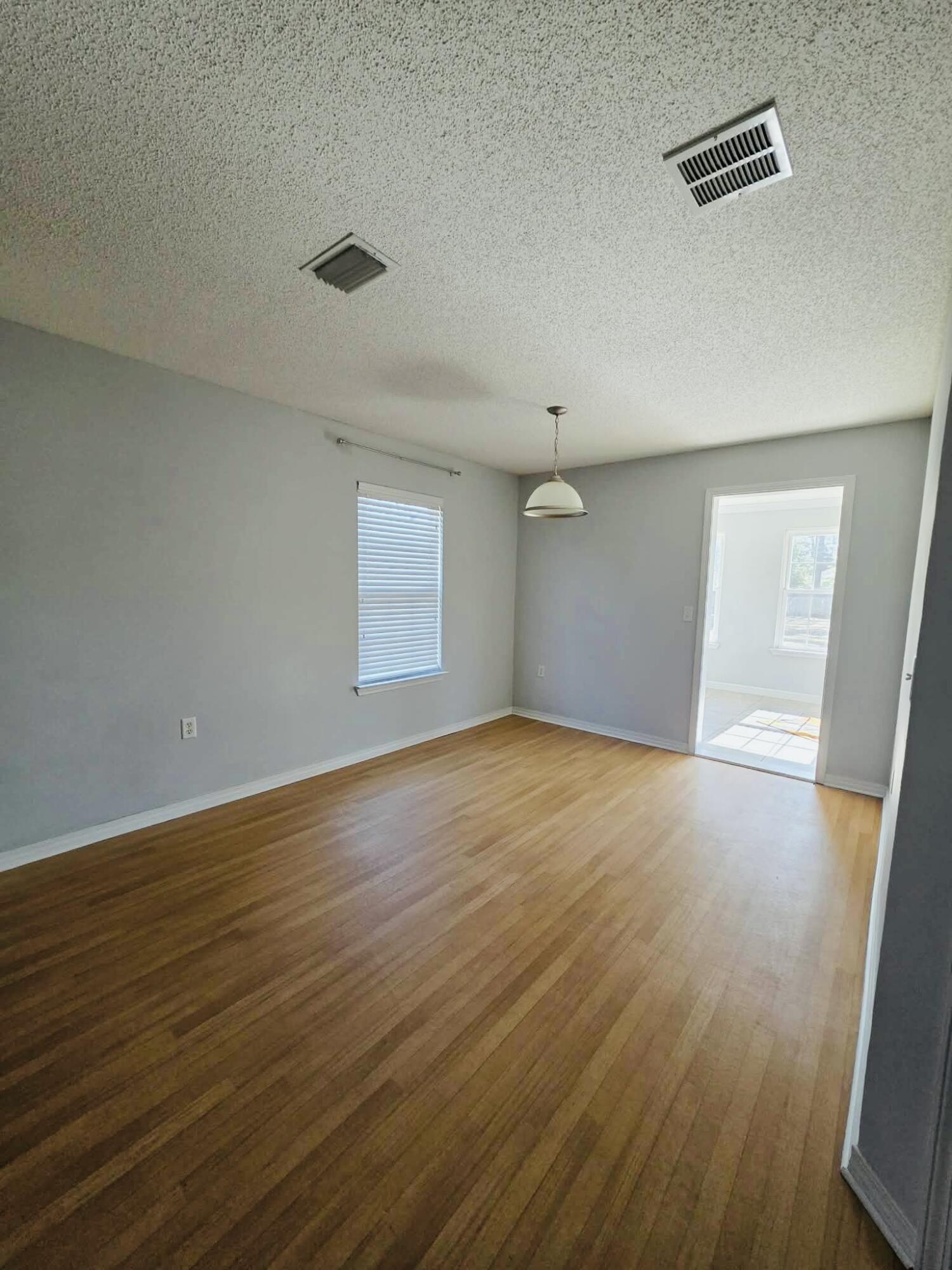 8347 Tavira Street Navarre, FL 32566 - Photo 10 of 49 an empty room with wooden floor and windows