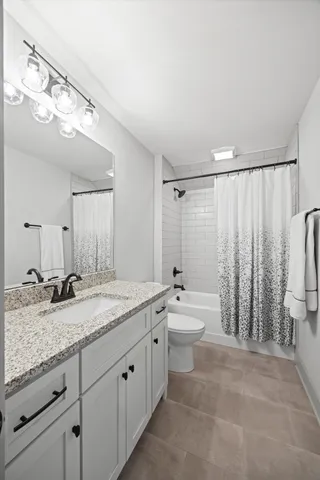 a spacious bathroom with a granite countertop sink a toilet a mirror and bathtub
