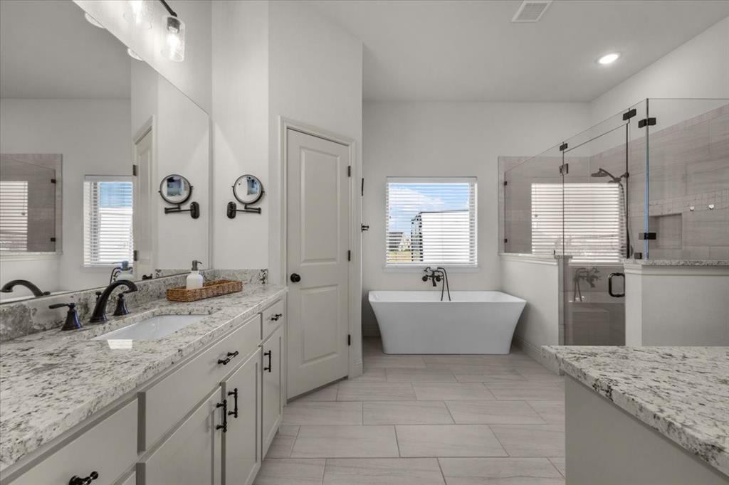 329 Palo Alto Drive Springtown, TX 76082 - Photo 16 of 34 Primary bathroom featuring a freestanding soaking tub, a large glass-enclosed shower with tiled walls, and dual vanity sinks with granite countertops