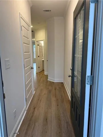 a view of a hallway with wooden floor and a bathroom