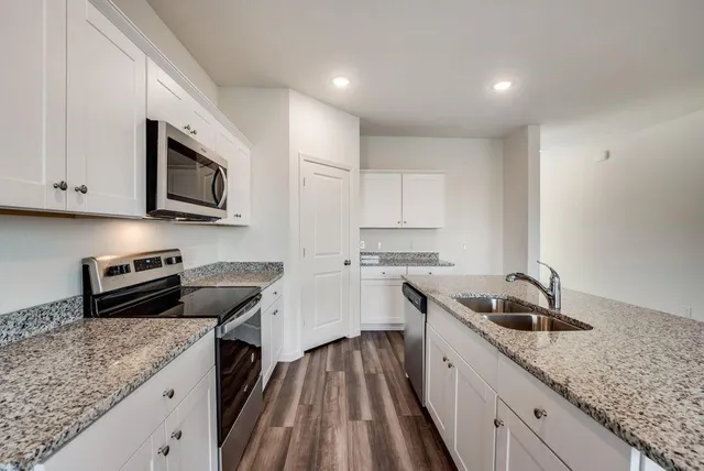a kitchen with granite countertop white cabinets sink and stainless steel appliances