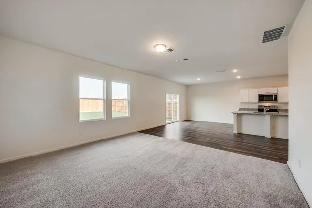 a view of empty room with kitchen and window