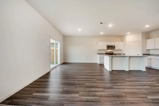 a view of kitchen with granite countertop refrigerator oven and white cabinets