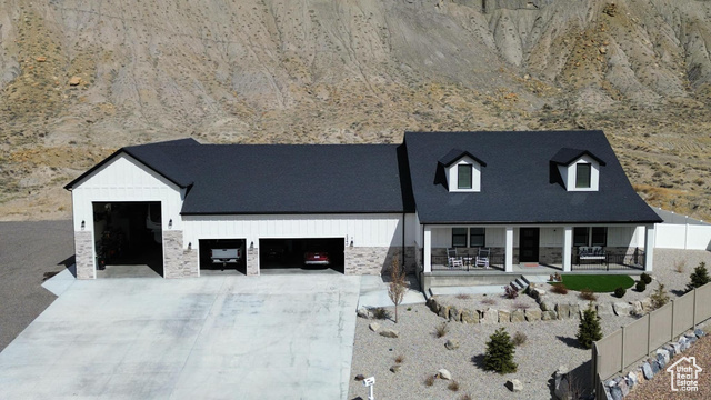 View of front of house with stone siding, concrete driveway, fence, and an attached garage