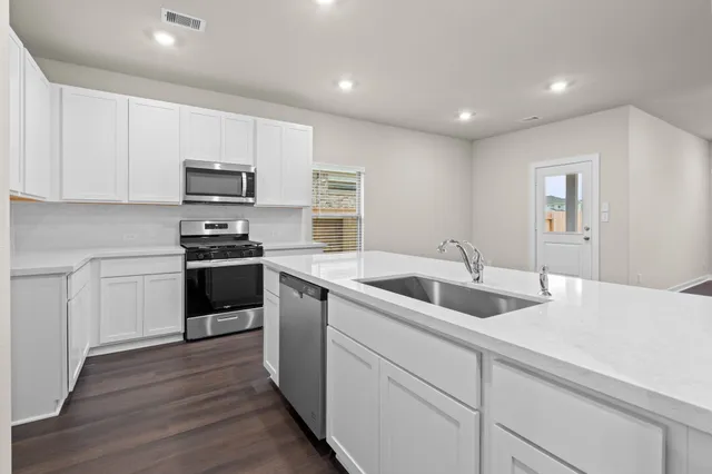 a kitchen with sink a microwave and cabinets