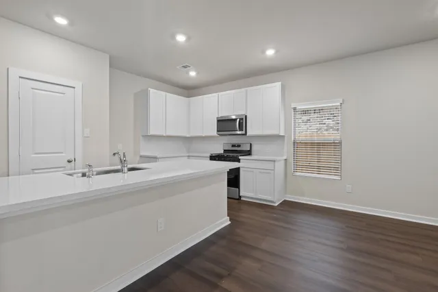 a kitchen with a sink cabinets stainless steel appliances and wooden floor