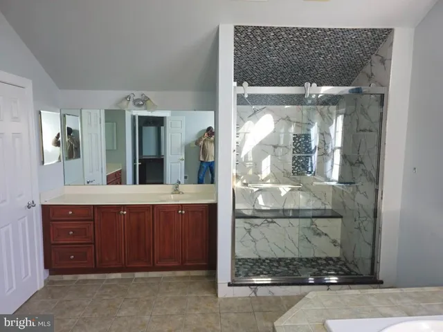 a bathroom with a granite countertop sink a mirror and a shower