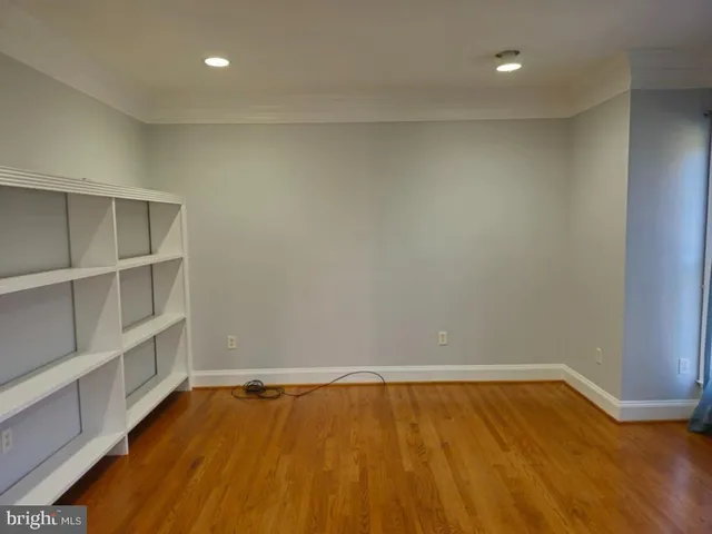 a view of an empty room with wooden floor and cabinet