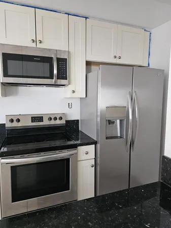 a kitchen with stainless steel appliances white cabinets and a stove top oven