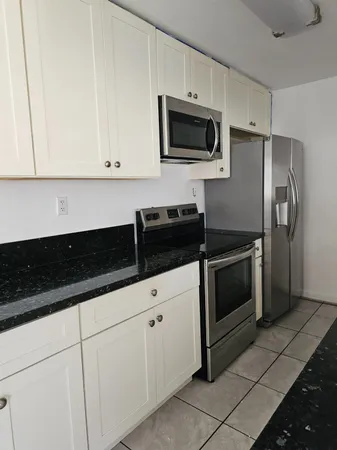 a kitchen with white cabinets a sink and stainless steel appliances