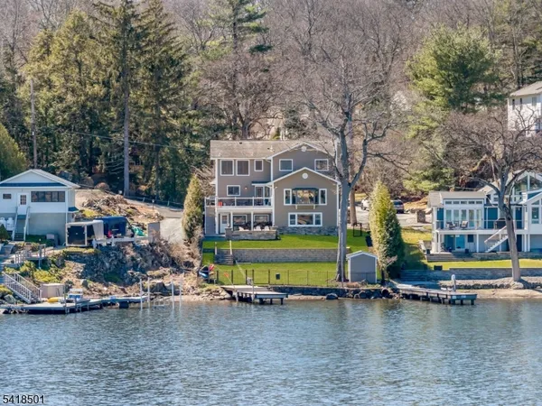 a view of a lake with a house and a yard with swimming pool