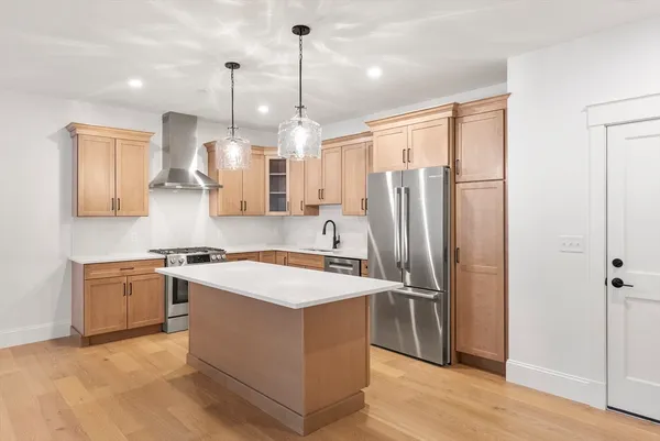 a kitchen with stainless steel appliances granite countertop a refrigerator a sink a stove and a wooden floors