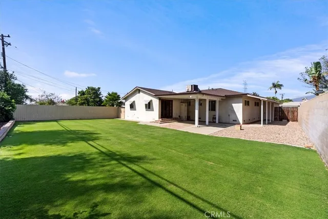 a white house with a big yard plants and large trees