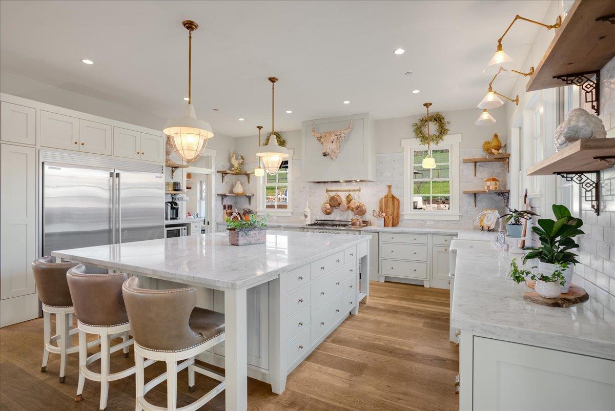 7670 Crews Road Gilroy, CA 95020 - Photo 42 of 83 a kitchen with stainless steel appliances kitchen island granite countertop a table chairs in it and wooden floors