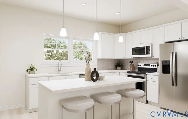 a kitchen with stainless steel appliances a sink a stove a refrigerator cabinets and a window