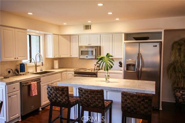 a kitchen with a sink a center island and stainless steel appliances