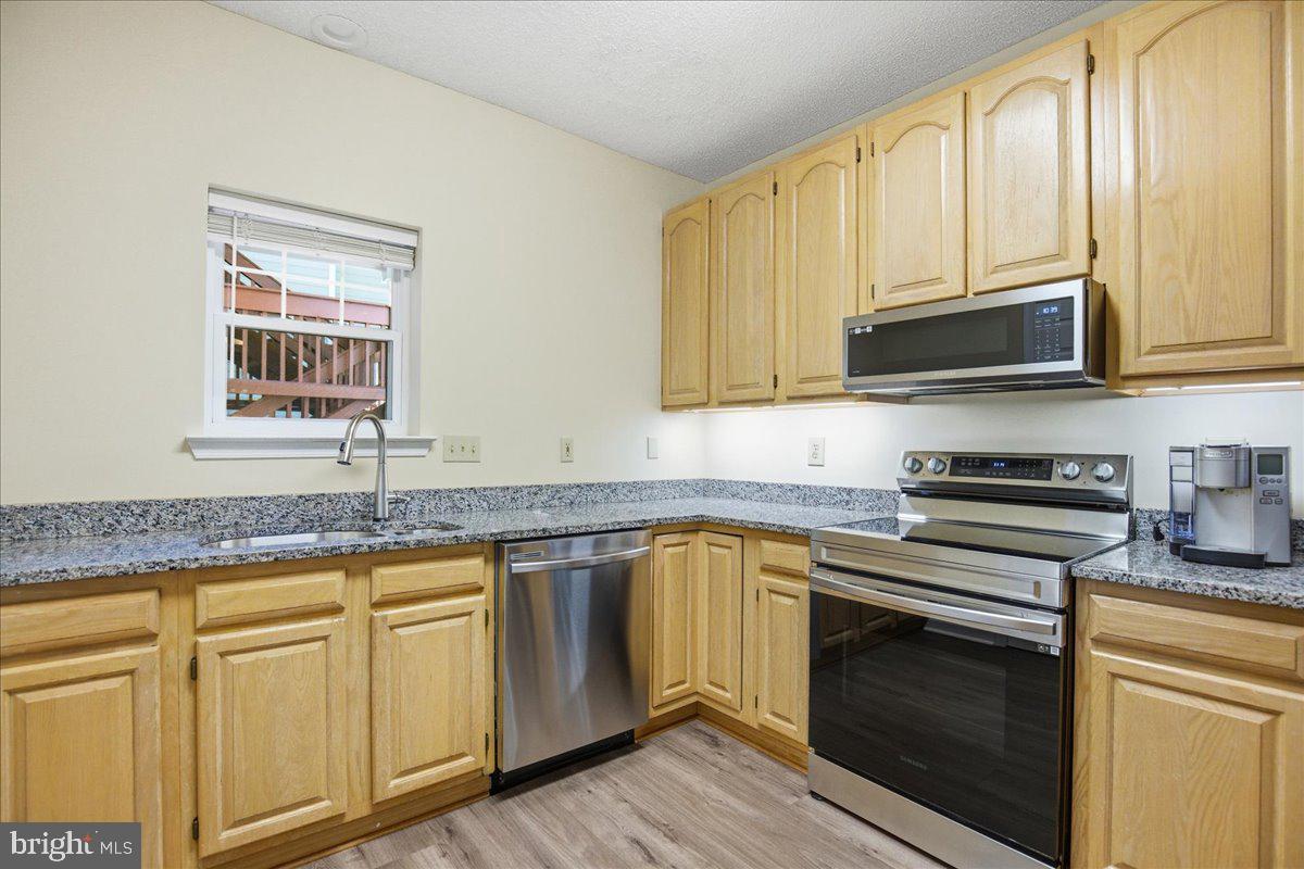 1126 Back Creek Loop, Unit 1126 Solomons, MD 20688 - Photo 11 of 47 a kitchen with granite countertop cabinets stainless steel appliances a sink and window