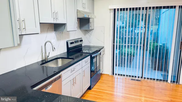 a kitchen with stainless steel appliances granite countertop a sink a stove and a wooden floors