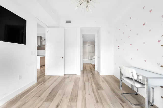 a view of a bedroom with wooden floor and bathroom