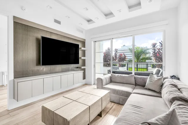 a living room with furniture a flat screen tv and a floor to ceiling window