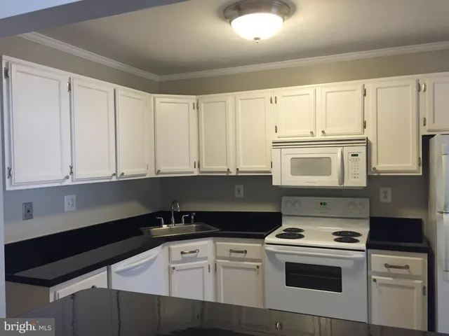 a kitchen with granite countertop white cabinets and white appliances