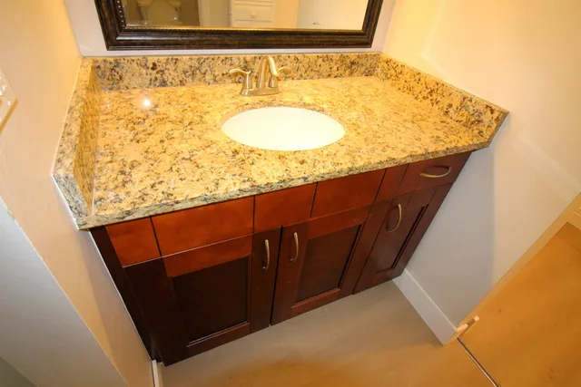 a bathroom with a granite countertop sink and a mirror