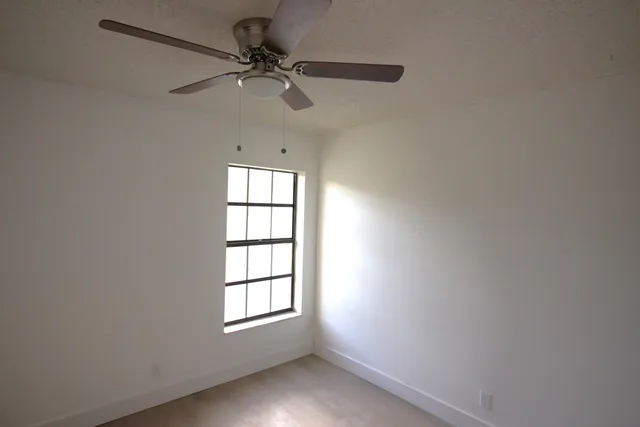 an empty room with a window and a fan