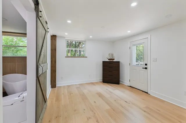 a view of an empty room with wooden floor and a window