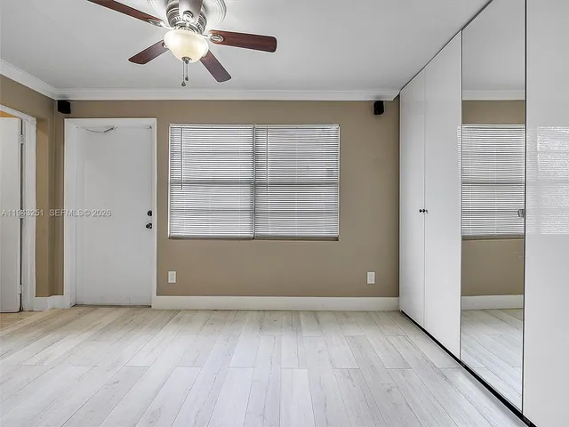 an empty room with windows and fan