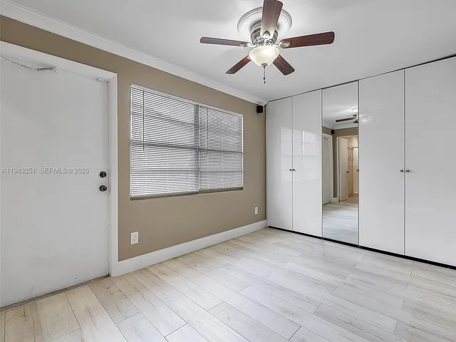 an empty room with wooden floor chandelier fan and windows
