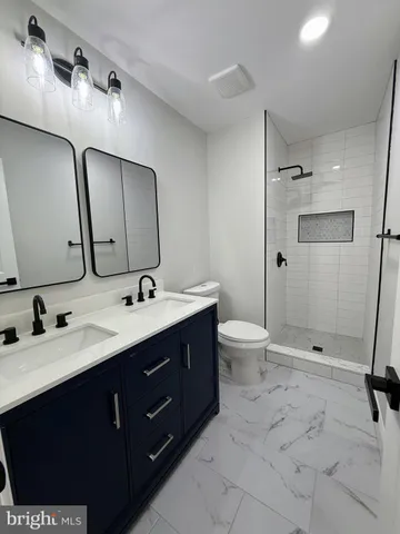a bathroom with a double vanity sink toilet and shower