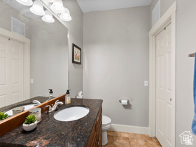 514 North Olympic Way Midway, UT 84049 - Photo 21 of 30 Vanity featuring a dark stone countertop with two undermount sinks, chrome faucets, and wood-finish cabinetry