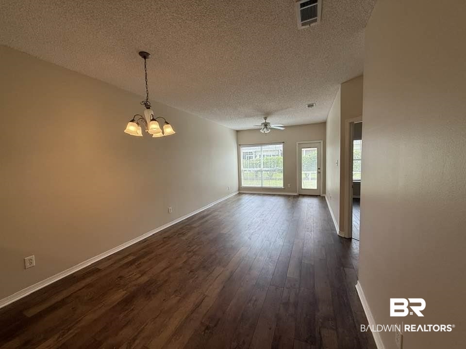 2651 South Juniper Street, Unit 401 Foley, AL 36535 - Photo 17 of 27 Unfurnished dining area featuring baseboards, a textured ceiling, and dark wood-style flooring