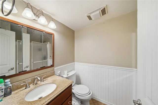 a bathroom with a granite countertop sink toilet a mirror and vanity