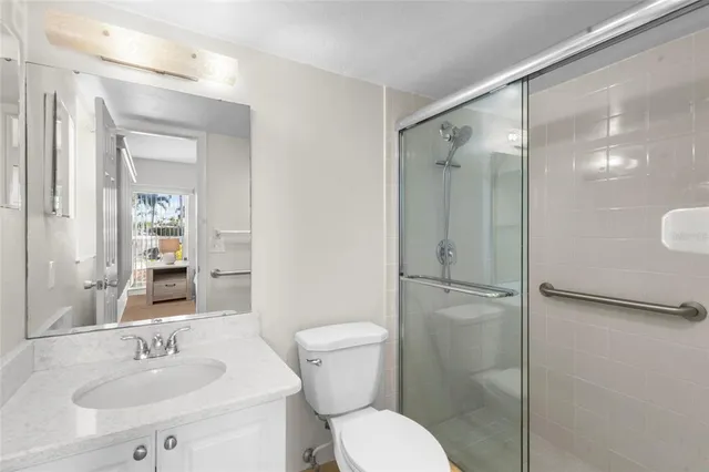 a bathroom with a shower sink vanity mirror and toilet