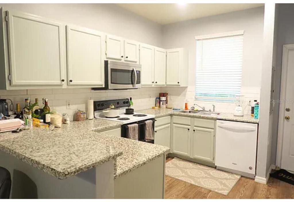 4415 Southwest 34th Street, Unit 308 Gainesville, FL 32608 - Photo 3 of 17 a kitchen with granite countertop a sink stove and white cabinets