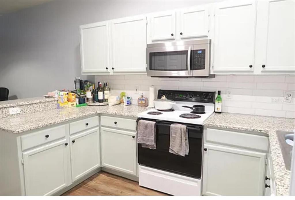 4415 Southwest 34th Street, Unit 308 Gainesville, FL 32608 - Photo 4 of 17 a kitchen with granite countertop white cabinets and white appliances