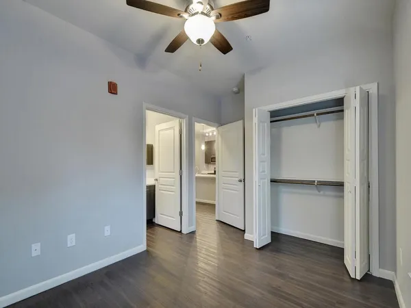 a view of empty room with wooden floor and fan