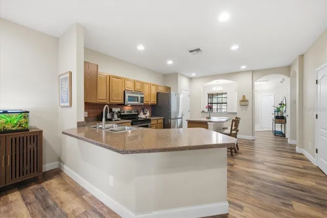 a large kitchen with stainless steel appliances granite countertop a large counter top and a wooden floors