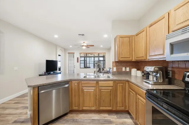 a kitchen with stainless steel appliances granite countertop a refrigerator a stove and a dining table with wooden floor