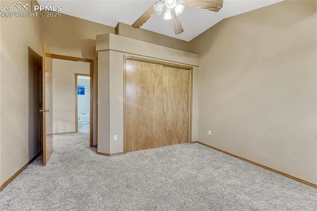 an empty room with a chandelier fan and closet