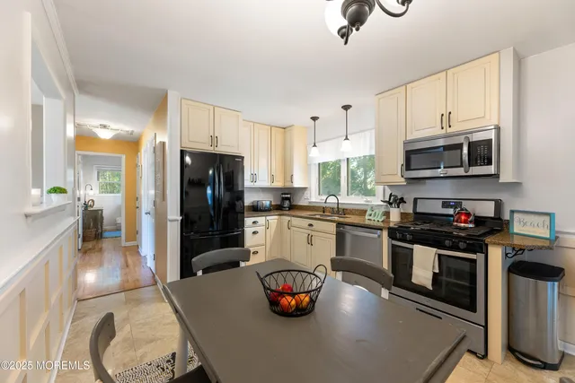 a kitchen with granite countertop a refrigerator a stove a sink and dishwasher with wooden floor