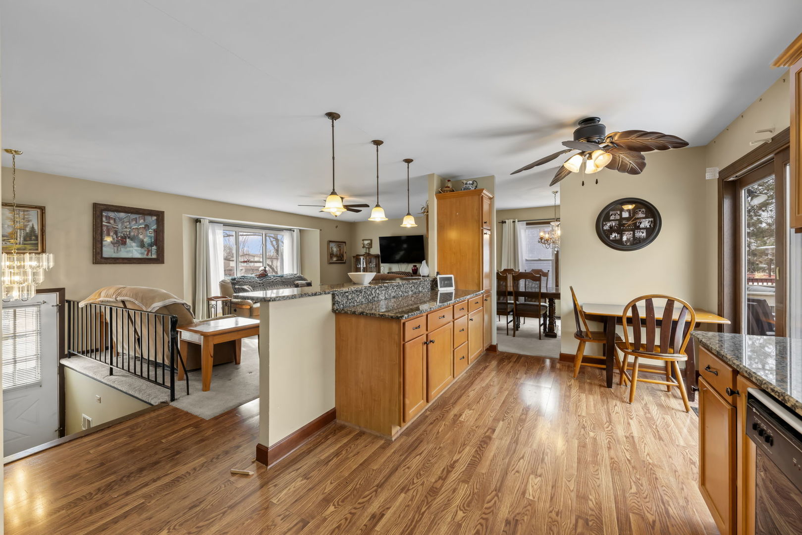580 Whitehall Way Bolingbrook, IL 60440 - Photo 9 of 25 a view of a dining room and livingroom with furniture wooden floor a rug a flat screen tv a painting and a chandelier