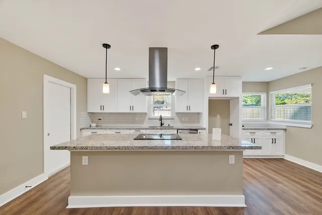 a kitchen with kitchen island stainless steel appliances sink stove and wooden floor