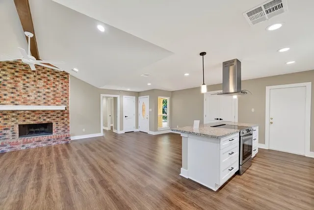 a kitchen with stainless steel appliances granite countertop a sink a stove and a wooden floors