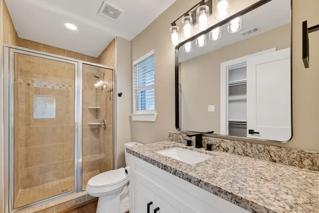a bathroom with a granite countertop sink toilet and shower